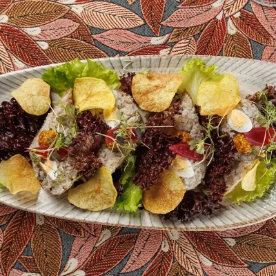 Бутерброд с форшмаком из филе сельди в еврейском стиле на обжаренном хрустящем ломтике хлеба, подаётся с маринованным красным луком, зернистой горчицей и тонкими картофельными чипсами и зеленью от Ресторана «Кухмистр»