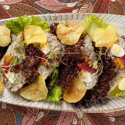 Бутерброд с форшмаком из филе сельди в еврейском стиле на обжаренном хрустящем ломтике хлеба, подаётся с маринованным красным луком, зернистой горчицей и тонкими картофельными чипсами и зеленью от Ресторана «Кухмистр»