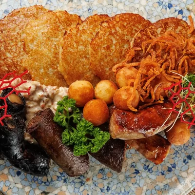 Дегустационный сет белорусских горячих закусок: три вида фирменных жареных колбас (свиная, печёночная и кровяная), жареные картофельные клёцки с соусом из грудинки, драники и сметана – от Ресторана «Кухмистр»