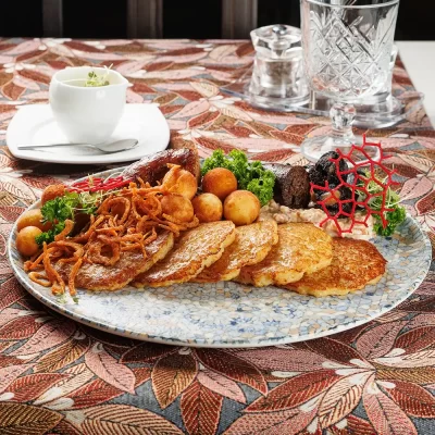 Дегустационный сет белорусских горячих закусок: три вида фирменных жареных колбас (свиная, печёночная и кровяная), жареные картофельные клёцки с соусом из грудинки, драники и сметана – от Ресторана «Кухмистр»