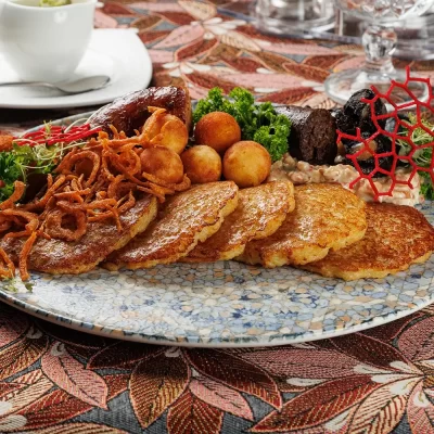 Дегустационный сет белорусских горячих закусок: три вида фирменных жареных колбас (свиная, печёночная и кровяная), жареные картофельные клёцки с соусом из грудинки, драники и сметана – от Ресторана «Кухмистр»