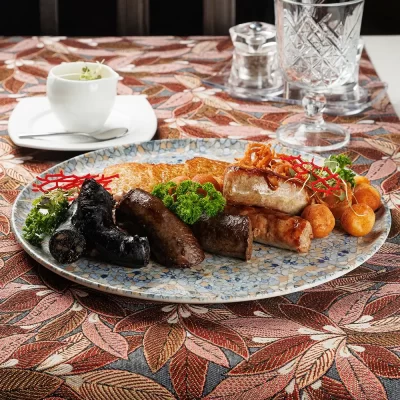 Дегустационный сет белорусских горячих закусок: три вида фирменных жареных колбас (свиная, печёночная и кровяная), жареные картофельные клёцки с соусом из грудинки, драники и сметана – от Ресторана «Кухмистр»