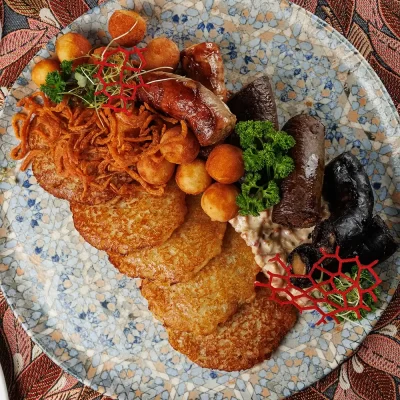 Дегустационный сет белорусских горячих закусок: три вида фирменных жареных колбас (свиная, печёночная и кровяная), жареные картофельные клёцки с соусом из грудинки, драники и сметана – от Ресторана «Кухмистр»