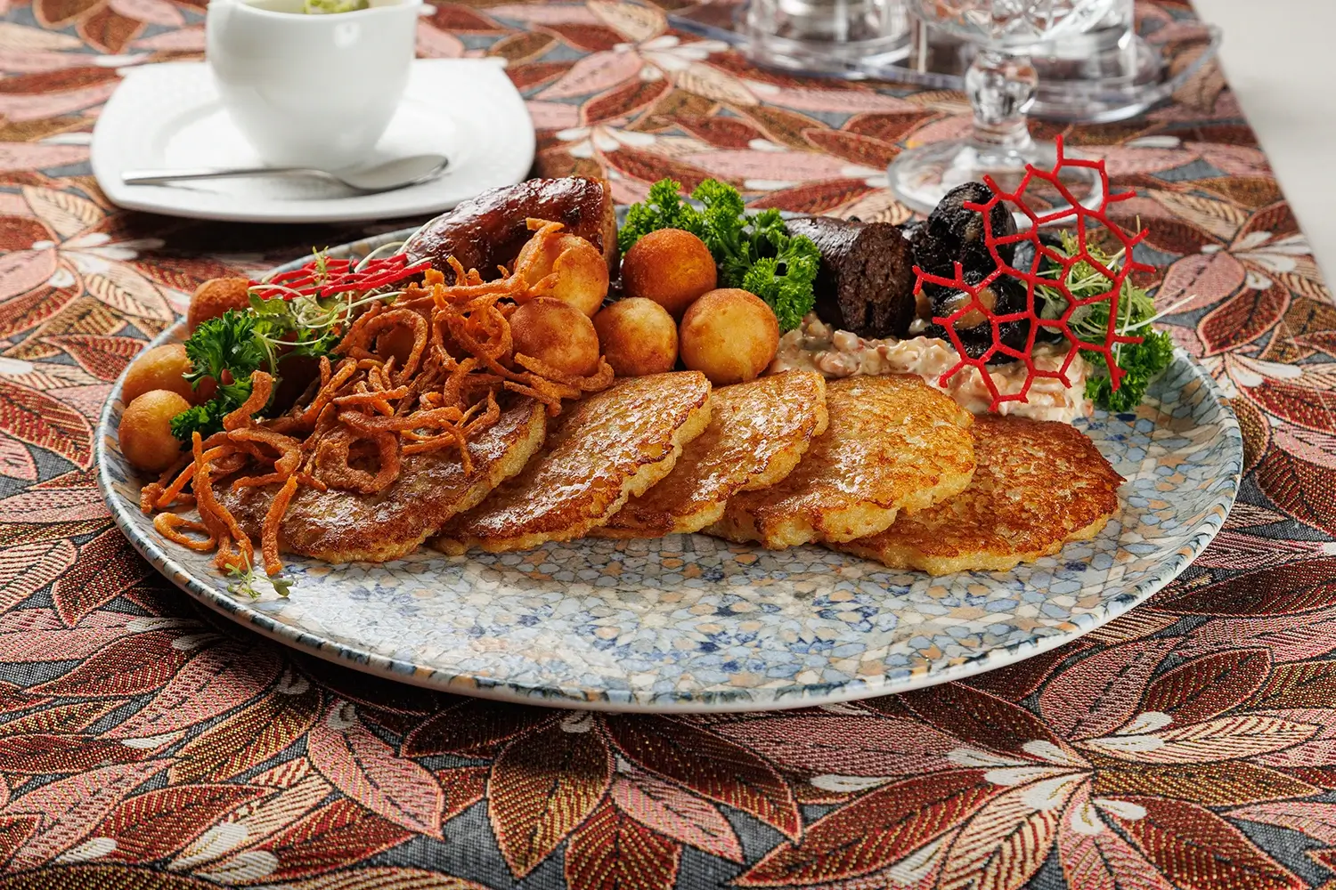 Дегустационный сет белорусских горячих закусок: три вида фирменных жареных колбас (свиная, печёночная и кровяная), жареные картофельные клёцки с соусом из грудинки, драники и сметана – от Ресторана «Кухмистр»