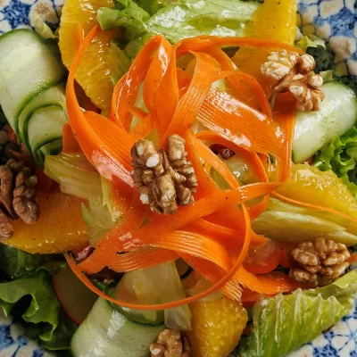Витаминный салат «Бабушкин» из свежих сельдерея, яблока, перца, моркови, зелёного салата, грецких орехов, огурца и апельсина, заправленный лимонным соком и оливковым маслом от Ресторана «Кухмистр»