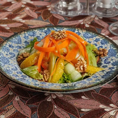 Витаминный салат «Бабушкин» из свежих сельдерея, яблока, перца, моркови, зелёного салата, грецких орехов, огурца и апельсина, заправленный лимонным соком и оливковым маслом от Ресторана «Кухмистр»