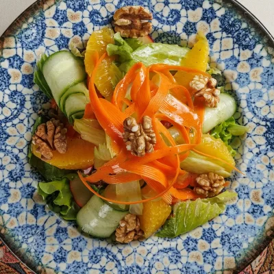 Витаминный салат «Бабушкин» из свежих сельдерея, яблока, перца, моркови, зелёного салата, грецких орехов, огурца и апельсина, заправленный лимонным соком и оливковым маслом от Ресторана «Кухмистр»